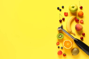 El blenderi ve sarı arka planda taze meyve püresi hazırlamak için farklı malzemeler.