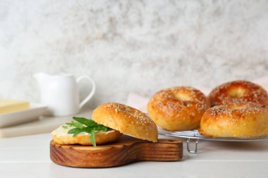 Beyaz ahşap masada tereyağı ve roka ile lezzetli simit panosu.