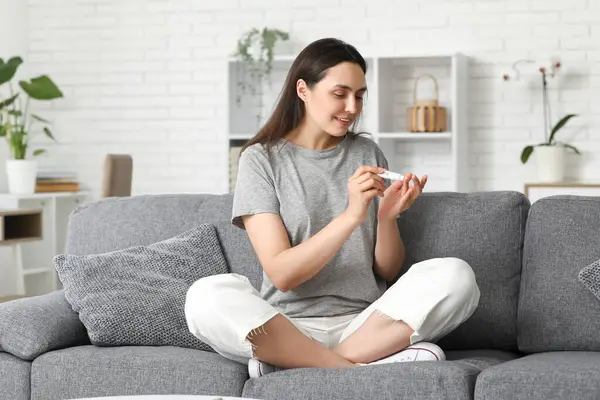 Şeker hastası genç bir kadın evdeki kanepede tükenmez kalem kullanıyor.