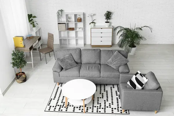 Gri kanepesi, koltuğu ve masası olan şık bir oturma odası.