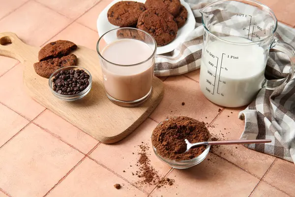 Lezzetli kurabiyeli bir bardak çikolata sütü ve bej fayanslı kakao tozu.