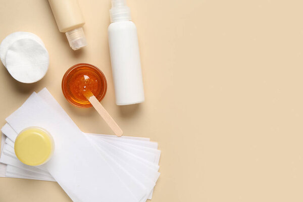 Состав с сахарной пастой, хлопчатобумажными прокладками и косметическими средствами на бежевом фоне, вид сверху. Концепция эпиляции