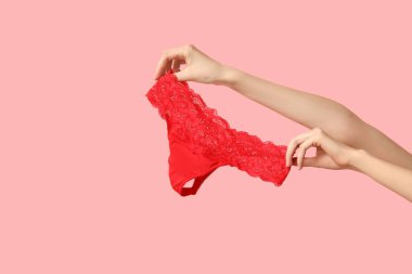 Pembe arka planda zarif dantel külotlu kadın eli, yakın plan.