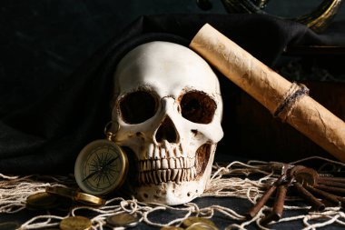 Korsan şapkalı kafatası, pusula ve hazine haritası karanlık masada, yakın plan.