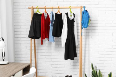 Şık okul üniforması ve açık tuğla duvarın yanında sırt çantası.