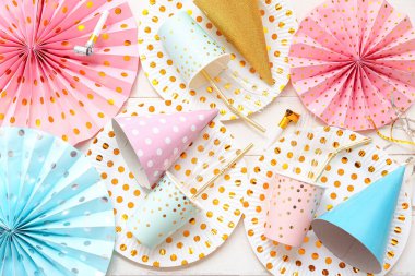 Hafif ahşap zemin üzerinde doğum günü partisi için kağıt tek kullanımlık sofra takımı ve dekor içeren kompozisyon