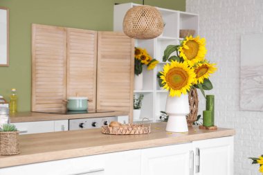 Beyaz tezgahları ve güzel ayçiçekleri olan şık bir mutfak.