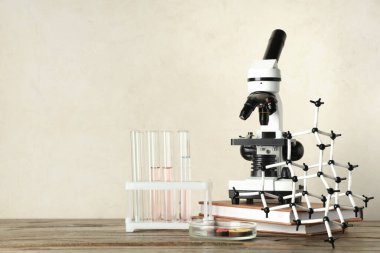 Beyaz grunge arka planına karşı ahşap masada kimyasal mataralar, moleküler modeller ve petri kabıyla modern mikroskop.