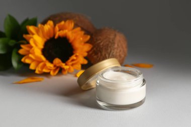 Gri arka planda kozmetik ürünü, hindistan cevizi ve ayçiçeği kavanozu