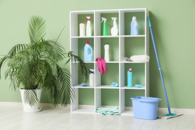Evde farklı temizlik malzemeleri, paspas ve kova olan raf ünitesi.