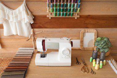 Atölyede dikiş makinesi, kumaş örnekleri ve iplik makaralarıyla terzinin işyeri