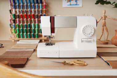 Atölyedeki terzi masasında kumaş örnekleri olan dikiş makinesi.