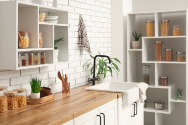 Mutfakta tezgah ve raflarda farklı ürünler olan cam kavanozlar.