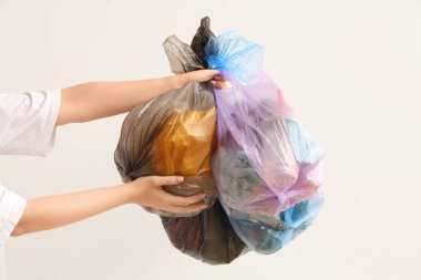 Beyaz arka planda çöp torbaları olan bir kadın.