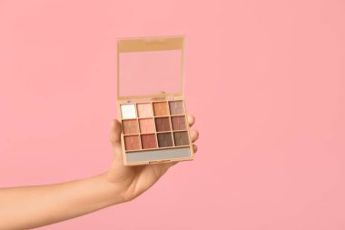 Pembe arka planda göz falı olan kadın eli.
