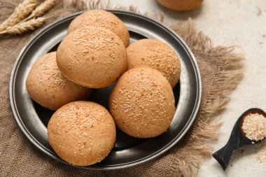 Susamlı taze çörekler ve beyaz arka planda buğday.