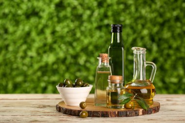 Dekan ve taze zeytinyağı şişeleri dışarıda, ahşap masada.