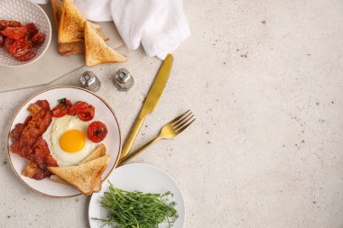 Beyaz arka planda kızarmış yumurta, pastırma, tost ve kurutulmuş domates tabağı. Üst görünüm