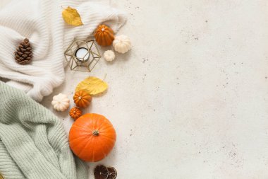 Şık, sıcak süveterler, mumlar ve arka planda sonbahar dekoru olan kompozisyon