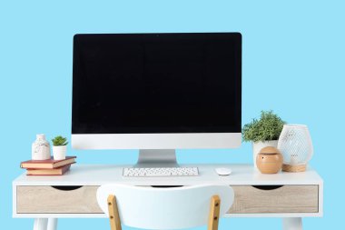 Boş bilgisayar monitörü ve mavi arka planda bitkileri olan modern işyeri