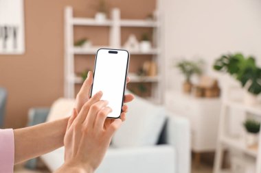 Evde boş cep telefonu olan bir kadın, yakın plan.