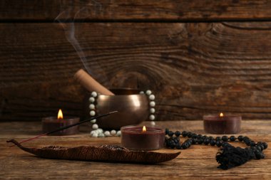 Yanan tütsü, mumlar, boncuklar ve tahta arka planda Tibet şarkı kasesi.