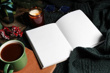 Kitap, dekorasyon, bir fincan çay ve kahverengi ahşap arka planda sıcak süveter içeren kış kompozisyonu