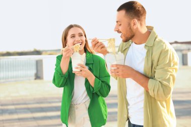 Öğle yemeği molasında sette Asya eriştesi yiyen genç bir çift.