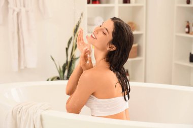 Güzel, genç, mutlu bir kadın evde banyo yapıyor.