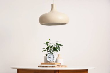 Masada kitaplar ve ışık duvarının yanında kolye bulunan çalar saat