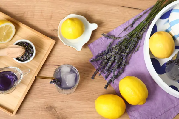 Bir bardak taze lavantalı limonata, çiçekler, limonlar ve meyve sıkacağı.