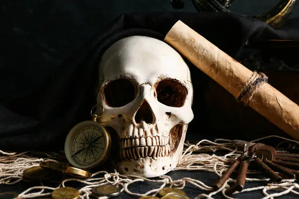 Korsan şapkalı kafatası, pusula ve hazine haritası karanlık masada, yakın plan.
