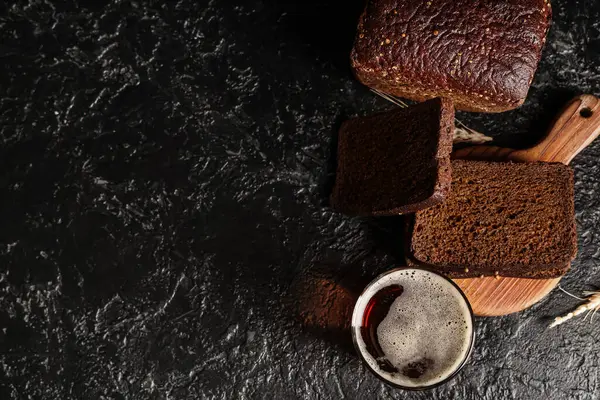 Bir bardak taze kvass ve siyah arka planda dilimler.