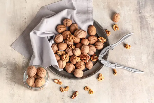 Gri arka planda lezzetli cevizli tabak ve kavanoz.