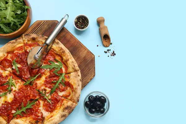 Lezzetli pizzalı kompozisyon, malzemeler ve mavi arka planda kesici.