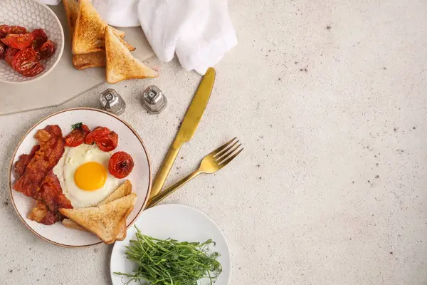 Beyaz arka planda kızarmış yumurta, pastırma, tost ve kurutulmuş domates tabağı. Üst görünüm