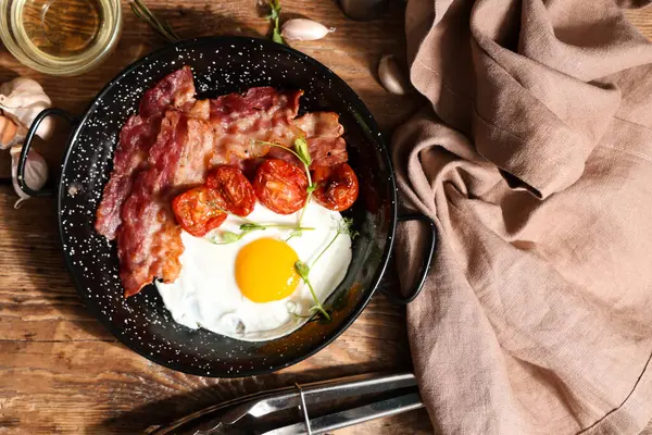Kızarmış yumurta, pastırma, kurutulmuş domates ve ahşap arka planda peçete. Yakın çekim.