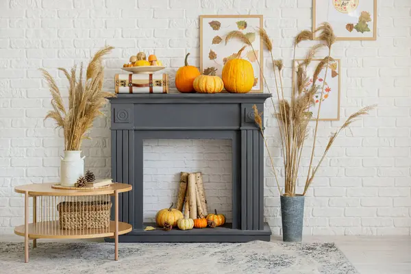 Şömineli şık bir oturma odası, kahve masası, vazo dolusu çim ve balkabağı. Sonbahar konsepti