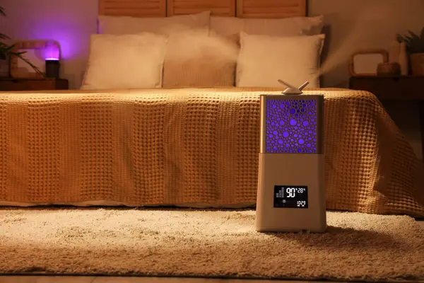 Karanlık yatak odasındaki modern hava nemlendiricisi.