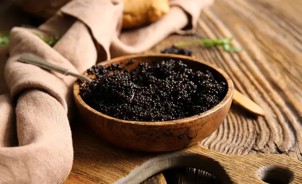 Ahşap arka plan üzerinde lezzetli siyah havyar ile kase