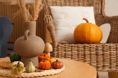 Oturma odasındaki masa üzerinde otlaklar ve balkabakları olan vazo, yakın plan.