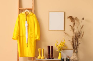 Koridorun içinde merdivende yağmurluk, çizme ve boş çerçeve var.