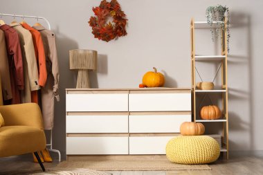 Çekmeceli, balkabaklı ve sonbahar kıyafetleri askıda asılı şık bir soyunma odası.