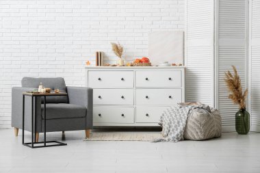 Balkabağı şeklinde yanan mumlar ve sehpanın üzerinde sonbahar yaprakları olan şık bir oturma odası.