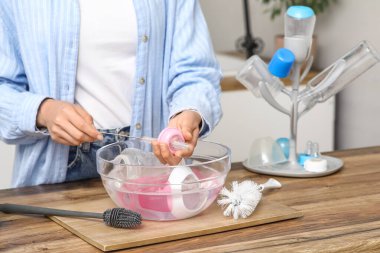 Mutfakta bebek şişesini fırçayla temizleyen kadın, yakın plan.