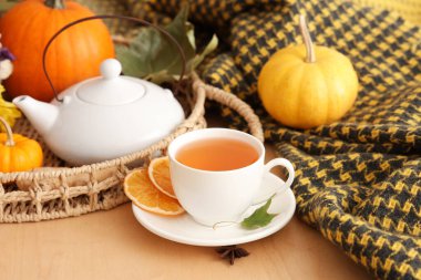 Çay demliği, bir fincan sıcak yeşil çay, balkabağı ve sonbahar yaprakları masada.