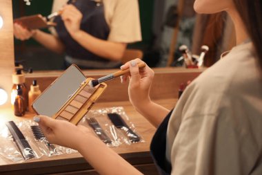 Geceleri soyunma odasında fırça ve göz farı olan kadın makyaj sanatçısı.