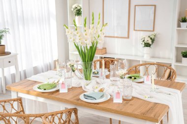 Gladiolus çiçekleri vazosu ve mutfak penceresinin yanındaki mumlarla süslü masa.