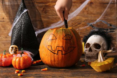 Süslü bir kadın, kahverengi ahşap arka planda Cadılar Bayramı için balkabağı Jack-O-Lantern 'in tohumlarını alıyor.