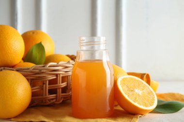 Bir şişe taze portakal suyu ve beyaz arka planda meyveler.